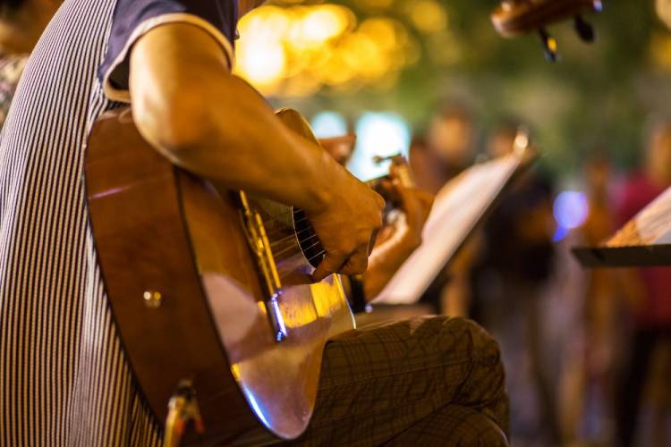man playing acoustic guitar at an outdoor show