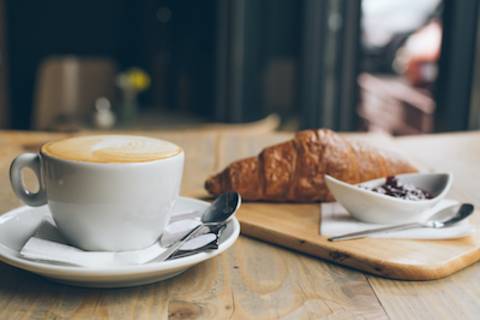 A coffee and pastry on a table in a coffee shop